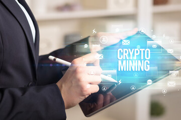 Close-up of a tablet searching CRYPTO MINING inscription, modern technology concept