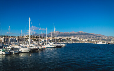 Fototapeta na wymiar Sailboats at the port of Altea with view on mountain range with old city and cathedral, Altea, Costa Blanca, Spain