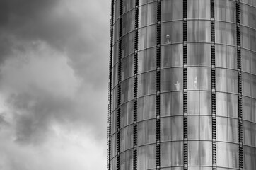 Black and White photo of the skyscraper and a dramatic skies somewhere in London. The miniature statue of Jesus Christ  is seen in the window.