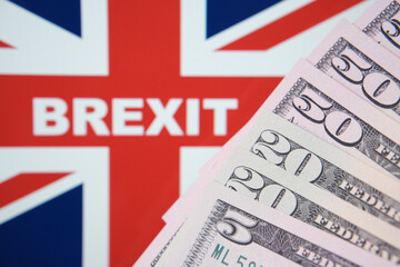 Word BREXIT on the United Kingdom flag on a background and banknotes on front. Selective focus.