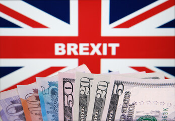 Word BREXIT on the United Kingdom flag on a background and different banknotes on front. Selective focus. Real photo, no alterations in post. Concept.