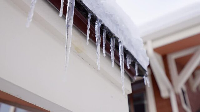 Huge thick icicles hanging from the roofs are melting under the spring sun