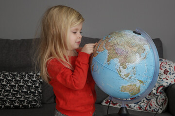 Portrait of adorable 3 years old girl playing with a globe.