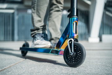 young teenager in sneaker on modern extreme stunt kick scooter in skatepark