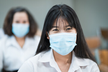 Cheerful college students in classroom wear protective face masks and use antiseptic for coronavirus prevention during coronavirus pandemic. Group of students wearing protection masks in class.