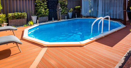 Above ground pool sunken below ground and surrounded by decking.