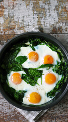 Eggs with spinach in a frying pan. Healthy breakfast. The keto diet.