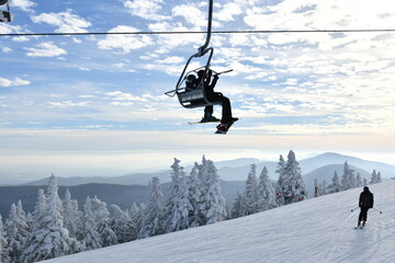 Chairlift with people at Stowe Ski Resort in Vermont, view to the Mansfield mountain slopes, December fresh snow on trees early season in VT,  hi-resolution image