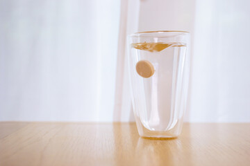 Tablet of calcium effervescent melting in a drinking water close up with copyspace.