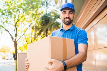 Delivery man carrying package outdoors.