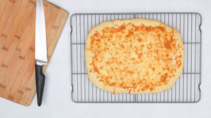 Homemade delicious flat bread with mozzarella cheese topping close up on cooling rack, flat lay