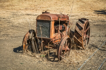 Historic Rusty Tractor on open hay field with fence