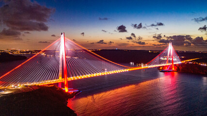 Obraz premium The miraculous view of Yavuz Sultan Selim Bridge, taken at sunset, illuminating the city with its lights.