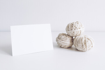Horizontal postcard mockup with white yarn on a white table background. Threads of cord boho image....