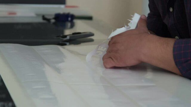 Foil cut in plotter. The man who removed the cut patterns on the cutting foil. The man removing the cut shapes from the vinyl.