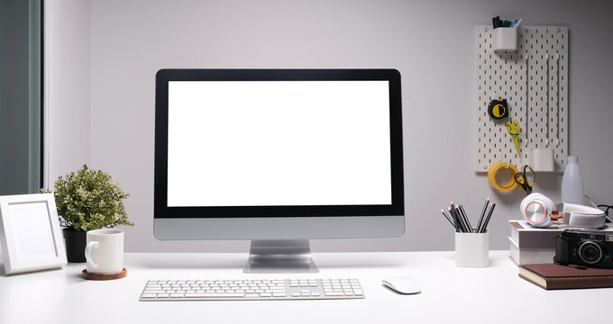Front view of a computer with blank screen and equipment on designer or photographer workspace. Blank screen monitor for graphic display montage.