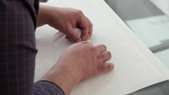 Foil cut in plotter. The man who removed the cut patterns on the cutting foil. The man removing the cut shapes from the vinyl.