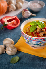 Pumpkin cream soup with roasted mushrooms and red bell pepper on blue background