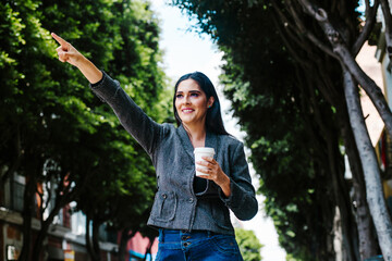 latin woman outdoor in the city hailing a taxi in a colonial city of latin america