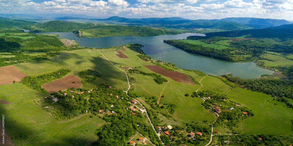 Poster An aerial shot of the green landscapes, fields and a river under the cloudy sky on a sunny day