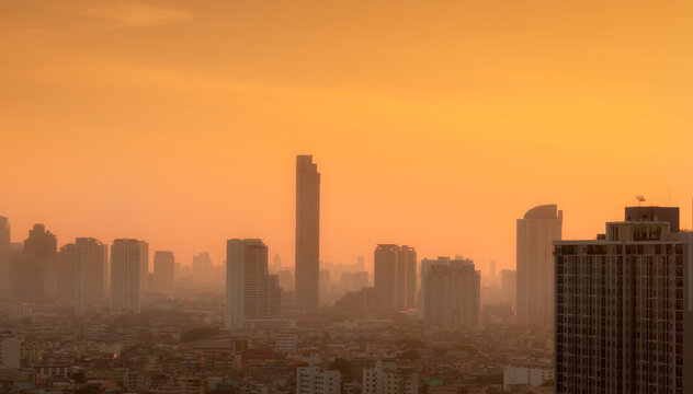 Air pollution in Bangkok, Thailand. Smog and fine dust of pm2.5 covered city in the morning with orange sunrise sky. Cityscape with polluted air. Dirty environment. Urban toxic dust. Unhealthy air.