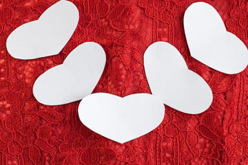 On a red openwork background are five white hearts with space for text. Romantic background.