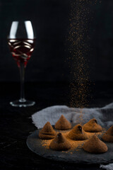 Delicious chocolate truffles and red wine on black background