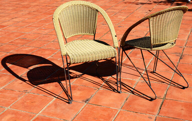 Two wicker chairs with shadows in the sunlight