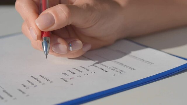 Woman puts a tick in the questionnaire with a red helium pen