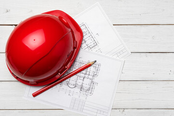 Hardhat and blueprints on wooden background top view
