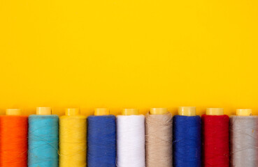 top view of Colored thread coils on yellow background, sewing, place for text