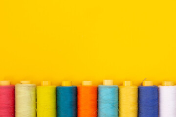 top view of Colored thread coils on yellow background, sewing, place for text