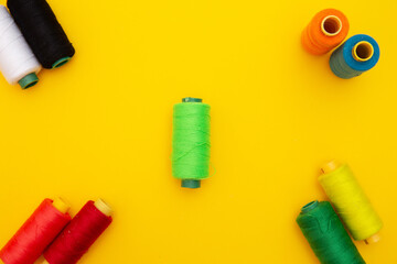 top view of Colored thread coils on yellow background, sewing, place for text