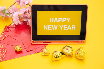 HAPPY NEW YEAR text on digital tablet screen with wireless keyboard isolated on yellow background