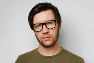 Obraz premium Portrait of a serious pensive young man against grey background