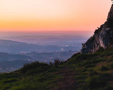 A Beautiful View Of A Cliff Overlooking The City Lights During Sunset