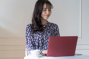 自宅でパソコンと携帯作業をするアジア人女性