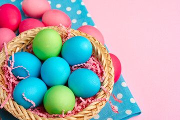 Fototapeta na wymiar Painted Easter eggs in decorative nest on pink background