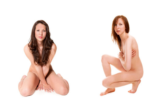 Two beautiful nude women covering themselves with their legs and arms, their private parts are not visible, isolated in front of white studio background