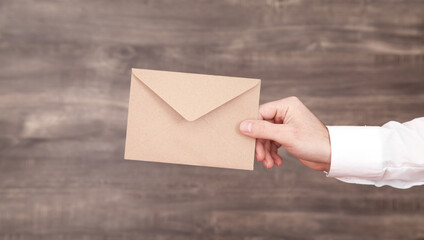 Male hand holding brown mail envelope.