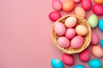 Painted Easter eggs in decorative nest on pink background