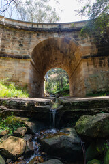 Fototapeta na wymiar Flowing water under Lennox Bridge, the oldest arch bridge in Australia.
