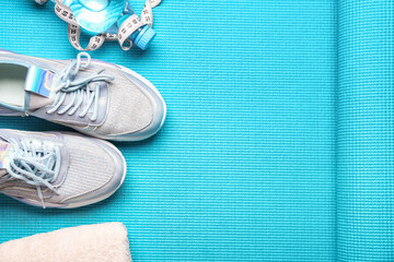 Sportive shoes, bottle of water and measuring tape on yoga mat