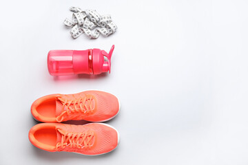 Sportive shoes, bottle of water and measuring tape on white background