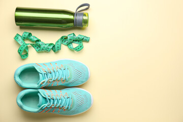 Sportive shoes, bottle of water and measuring tape on light background