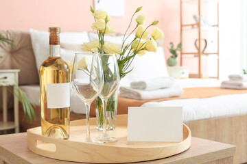 Tray with bottle of wine and glasses on table in hotel honeymoon room