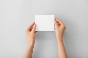 Female hands with blank paper on light background