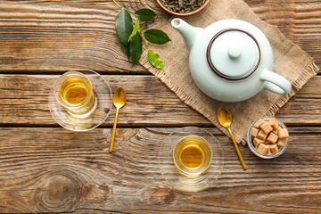 Composition with cups of green tea and teapot on wooden table