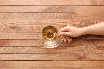 Female hand with cup of green tea on wooden table