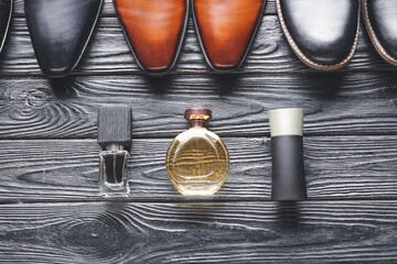 Bottles of perfume and male shoes on wooden background